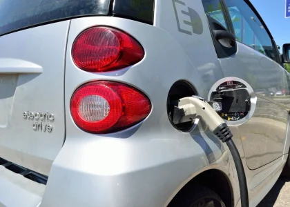 A small silver electric car plugged in at a charging station