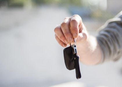 A hand holding out a set of car keys