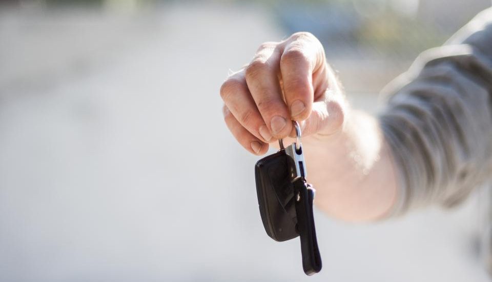 A hand holding out a set of car keys