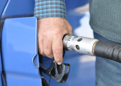A hand holding a fuel nozzle at a car's filler