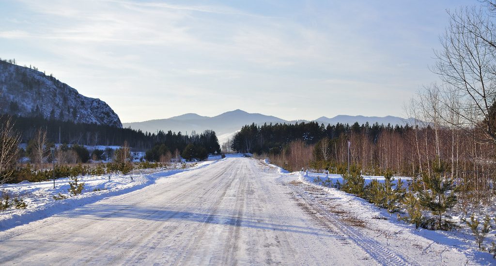 A snow-covered road leading toward distant mountains
