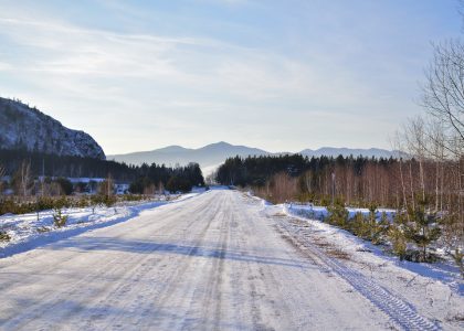 A snow-covered road leading toward distant mountains